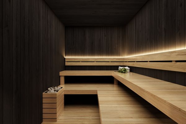 Modern wooden sauna with dark walls, tiered light wood benches, ambient lighting, and a small bucket on a bench.