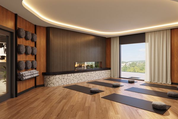 Modern yoga studio with wooden floors, mats, meditation cushions, fireplace, and large window with a view.