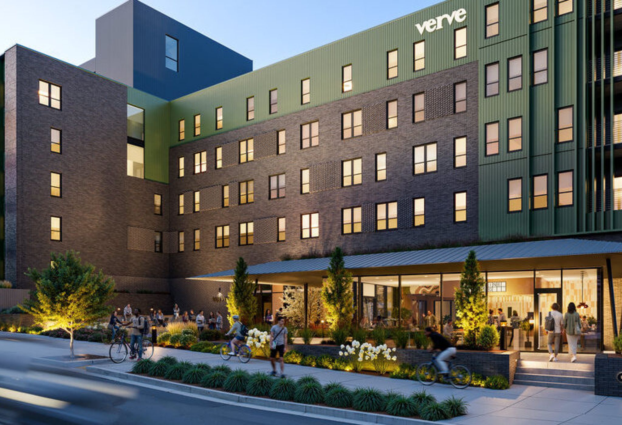 Modern apartment building with green and brick exterior, people walking and biking, and a coffee shop at street level.