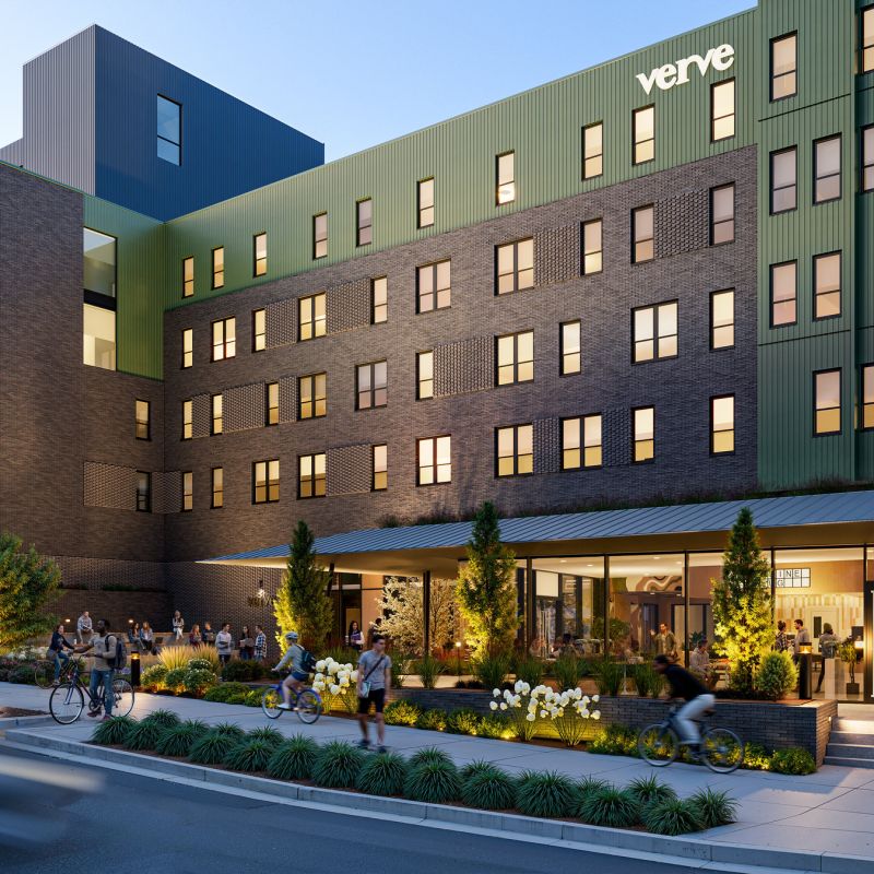 Modern multi-story apartment building with people outside, greenery, and a coffee shop on the ground floor.